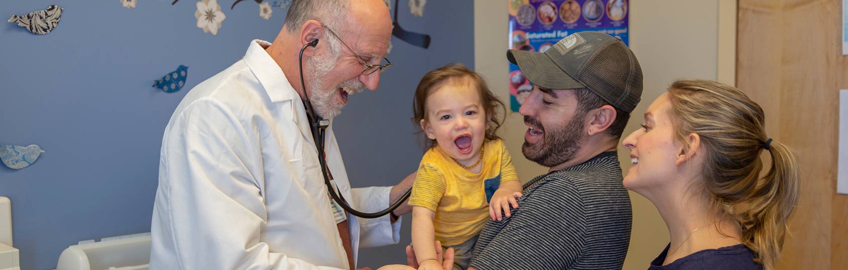 Médico com família e criança na sala de exame.