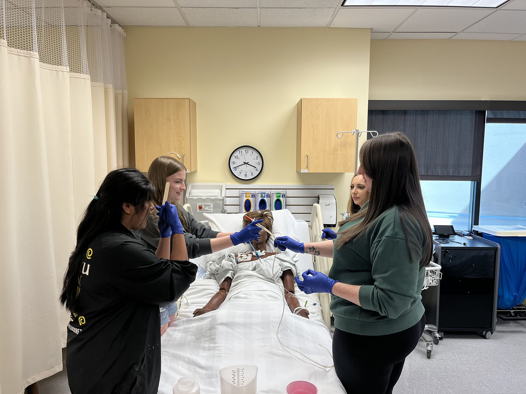 High school students attend to a dummy in a hospital bed