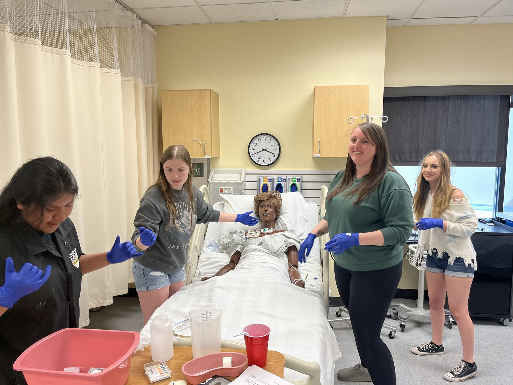 High school students attend to a dummy in a hospital bed