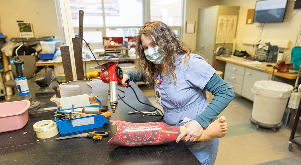 An orthotics and prosthetics provider repairing a prosthetic leg