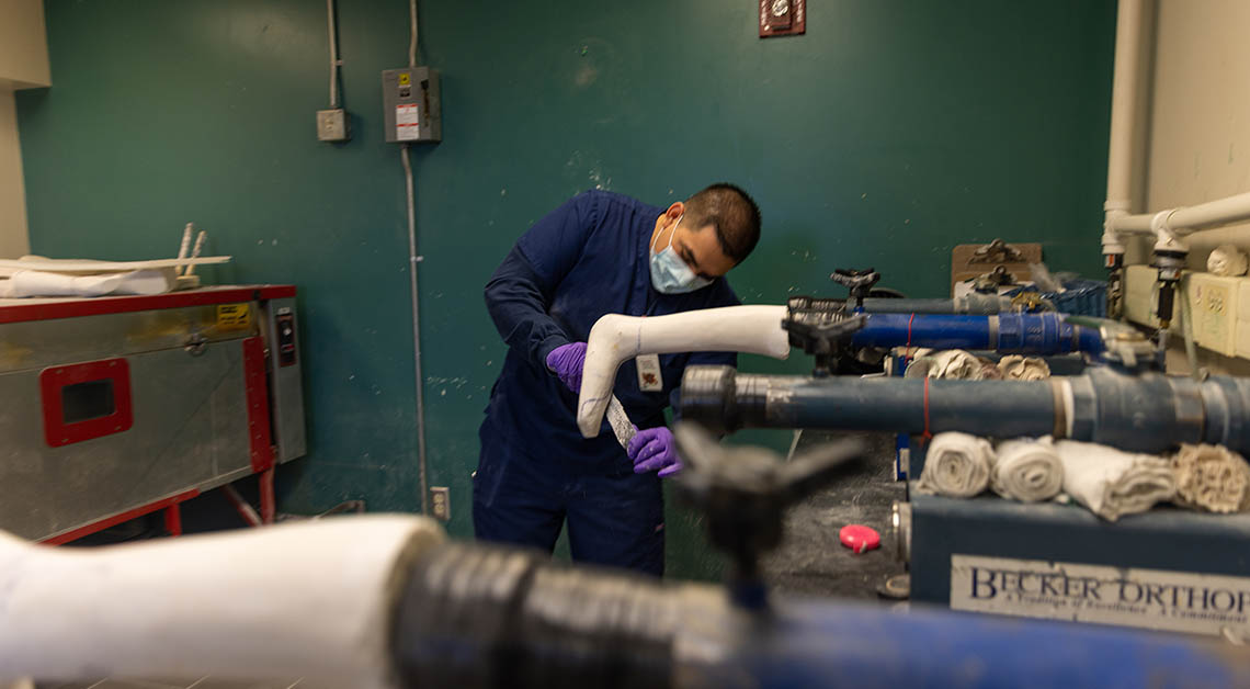 A prosthetics provider adjusting a mold for a prosthetic leg