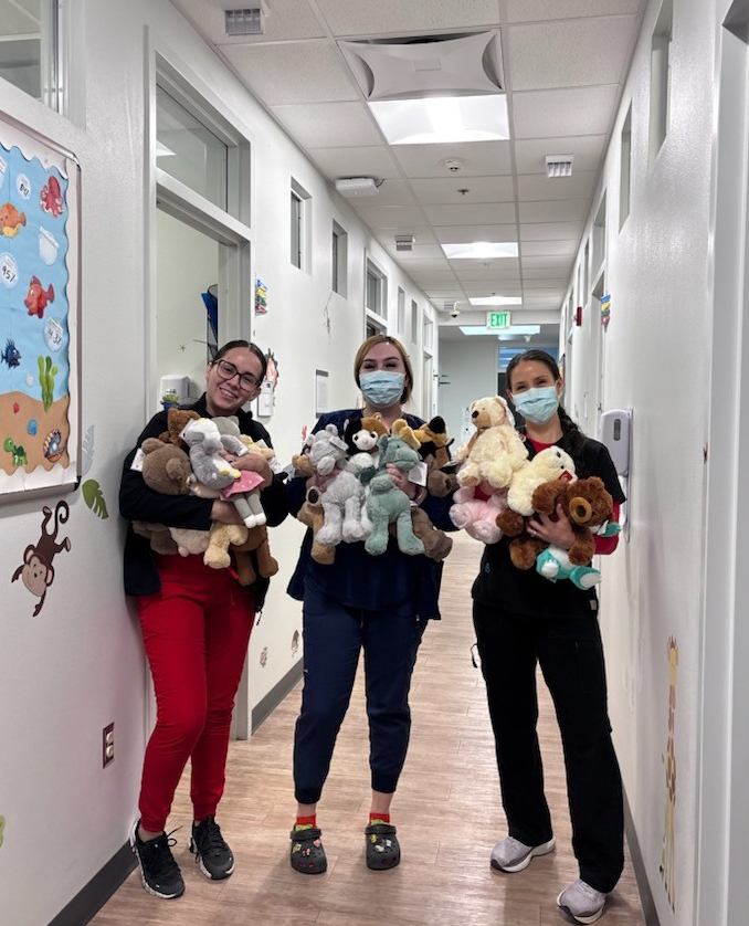 Three pediatric nurses hold up toys for the 2024 toy drive