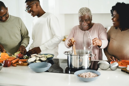 A black family preparing dinner together around a big countertop