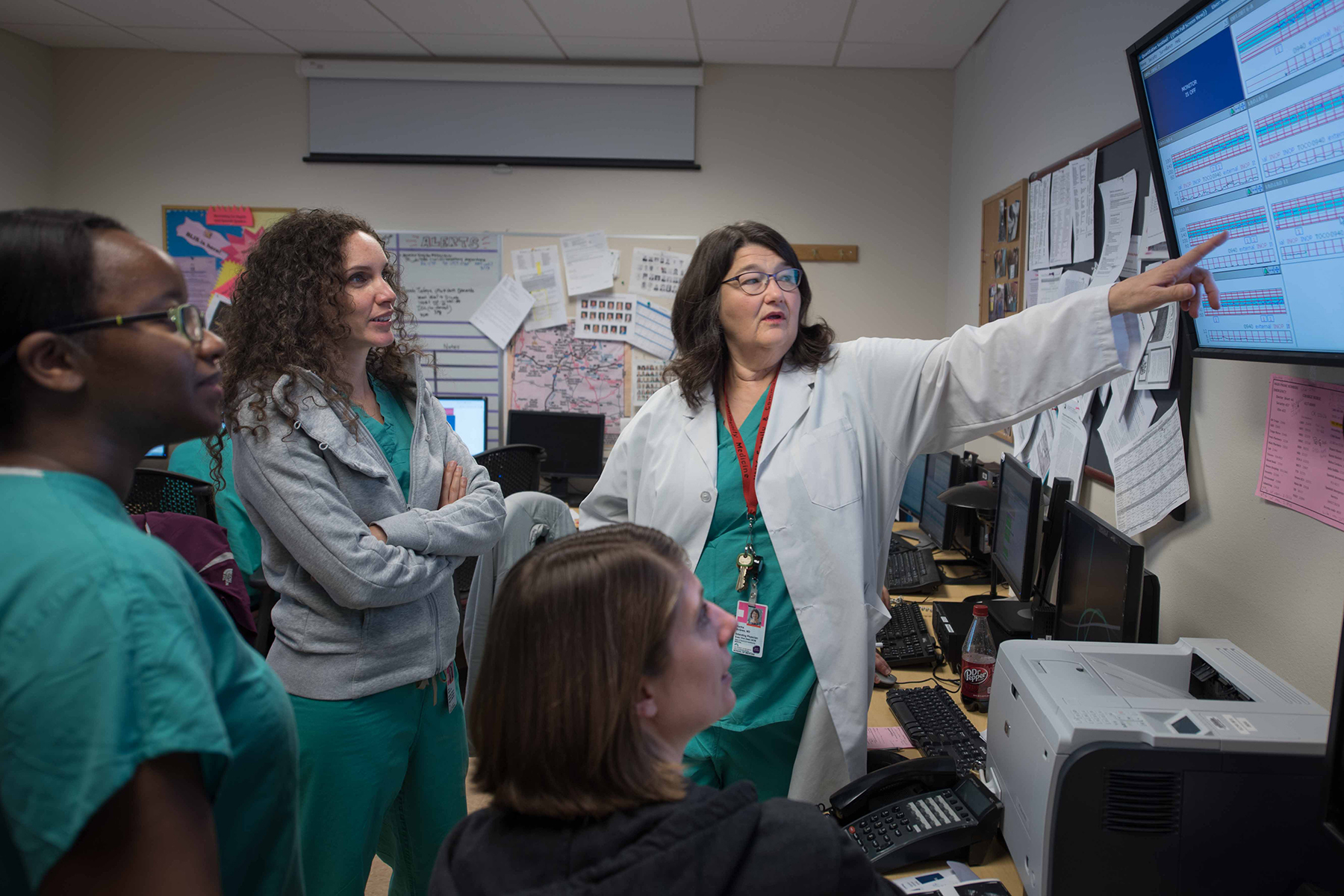 A group of medical researchers look at test results and data on a screen