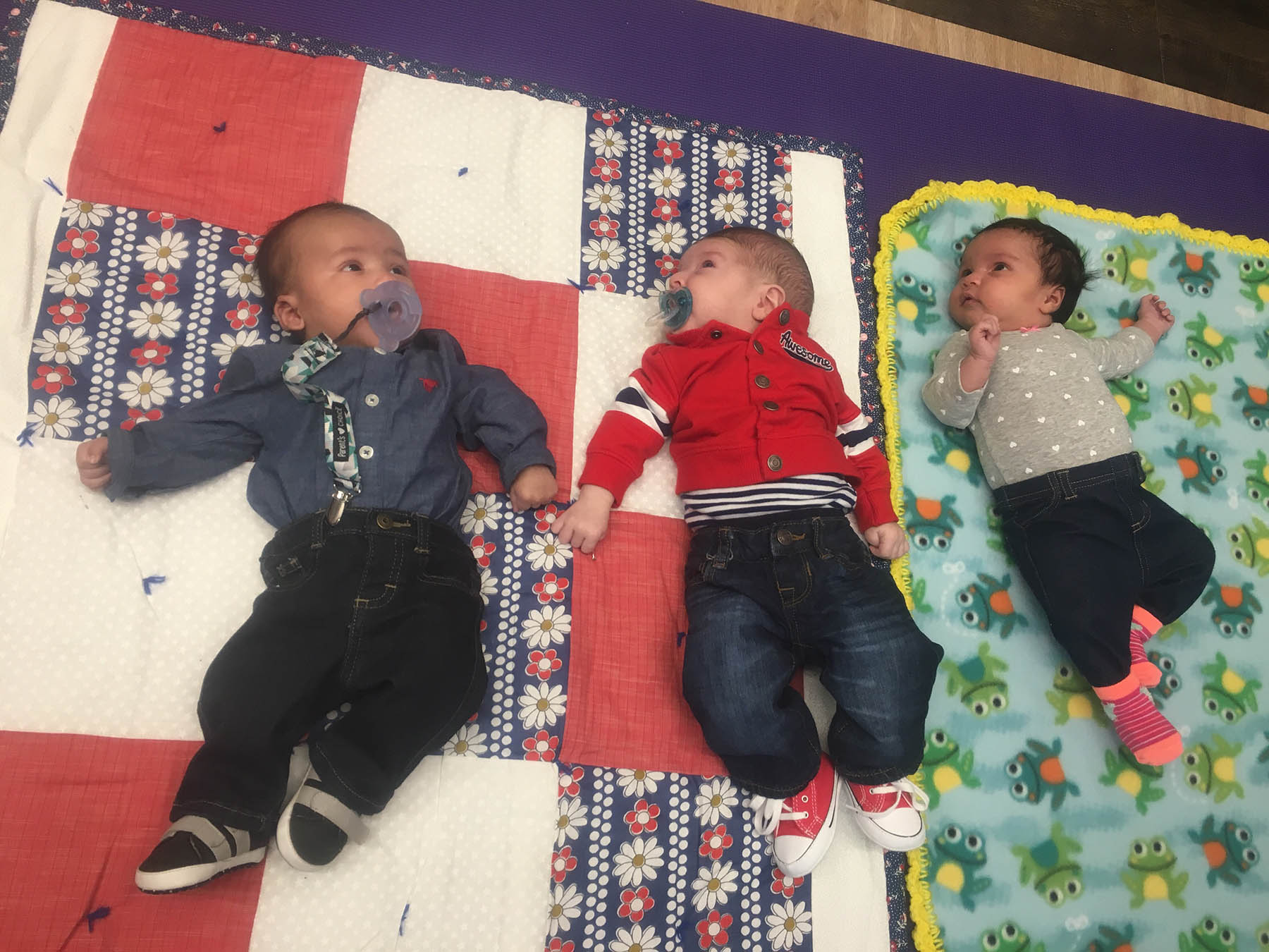Three babies laying down on a blanket
