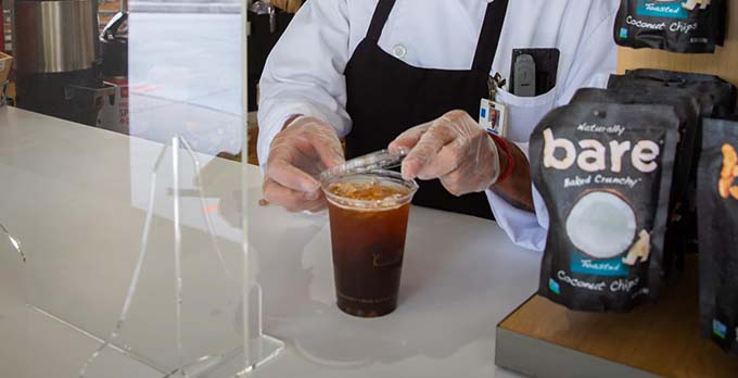 Ein Café-Mitarbeiter bereitet eine Tasse Kaffee zu