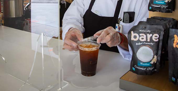 Un trabajador de la cafetería preparando una taza de café.