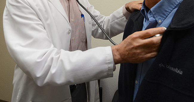 Doctor holding stethoscope to patient