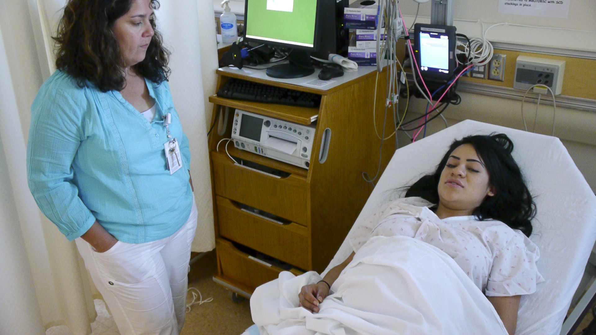An expected mother laying on a bed with a provider standing next to them