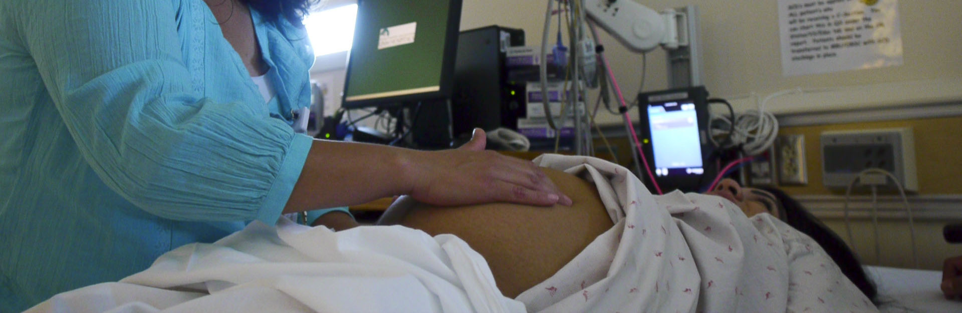 A provider examining a pregnant person's abdomen