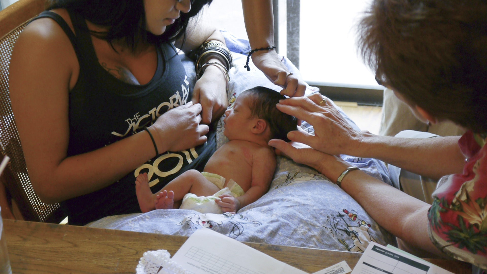 A mother and nurse attend to the mother's newborn