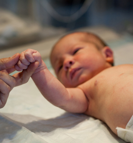 Bebé sosteniendo el dedo de un adulto.