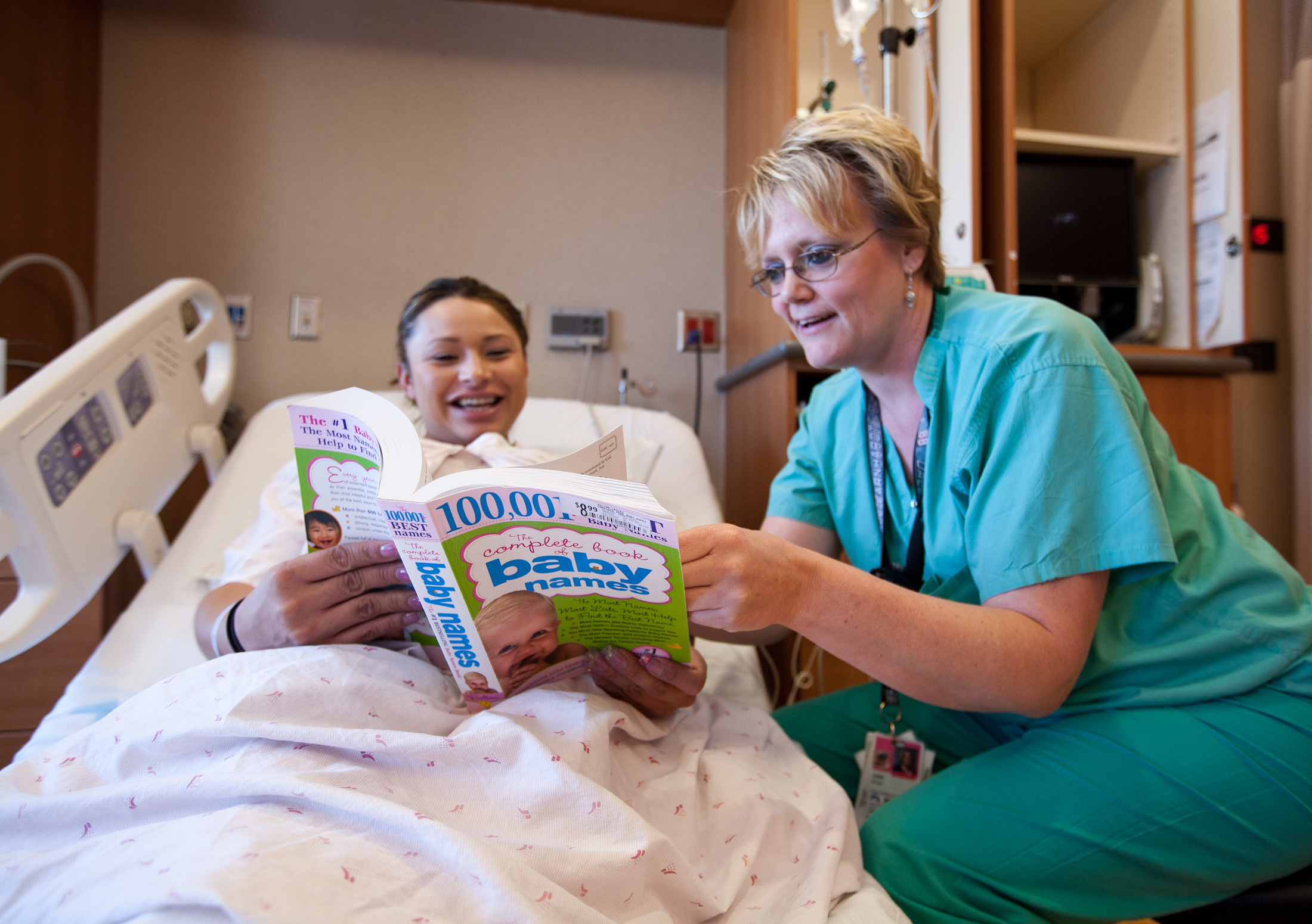 Eine werdende Mutter und eine Krankenschwester gehen ein Buch mit Babynamen durch