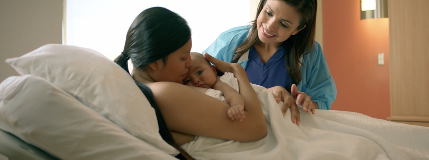 A woman holding her baby with a midwife