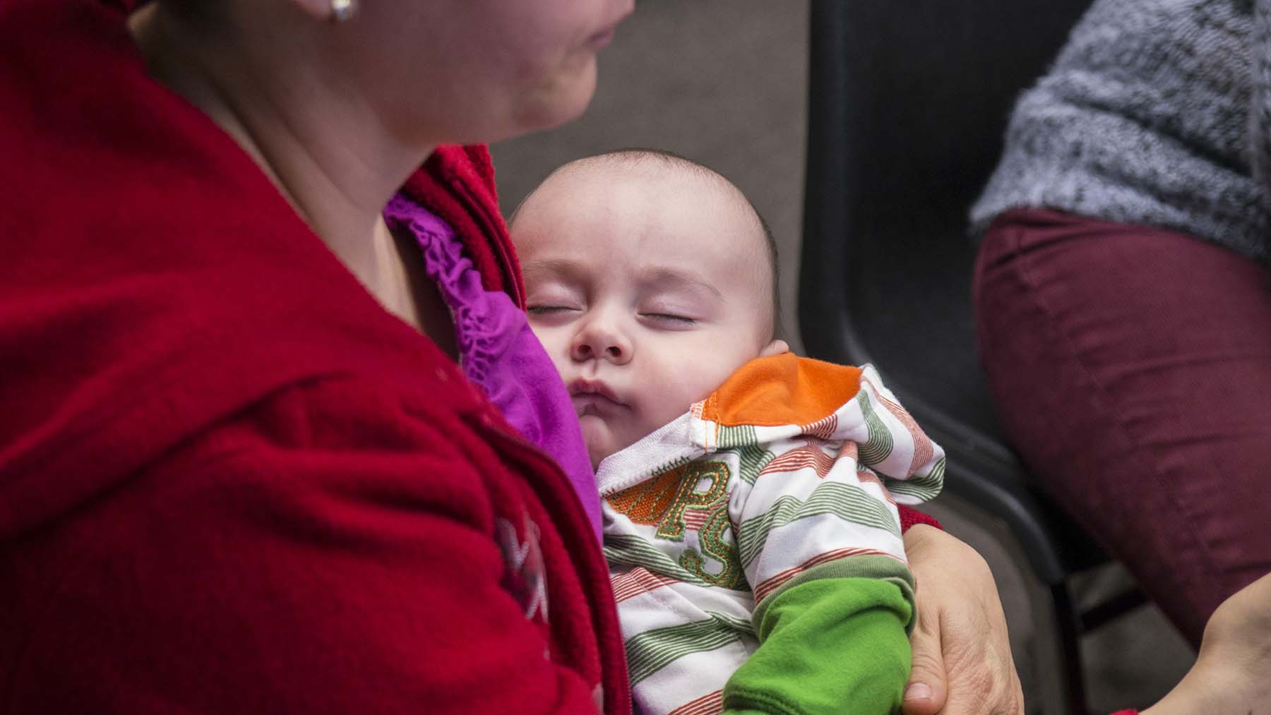 A baby sleeping in it's parents arms