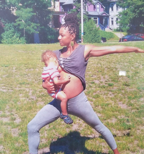 Donnyelle Miller breastfeeding her child while striking a yoga pose.