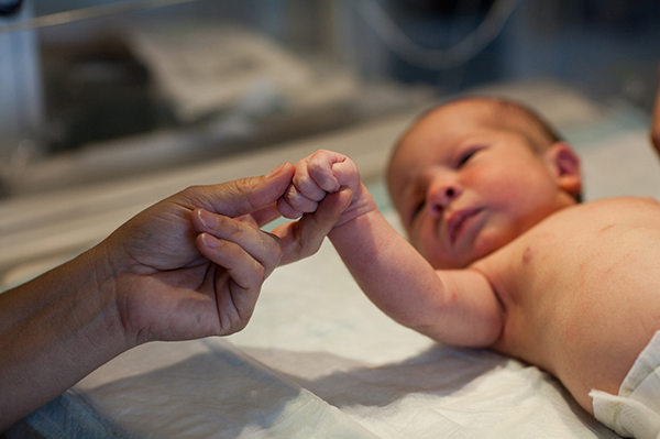 Ein Baby, das sich an einer Hand festhält