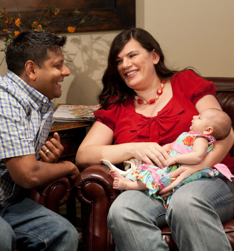 Husband looking fondly at wife holding baby,