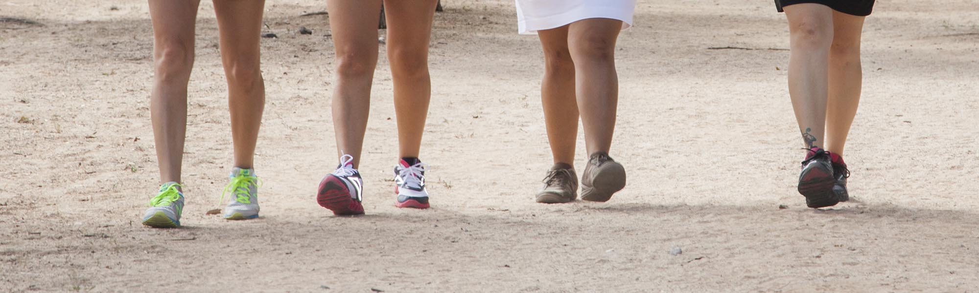 Four people, faces not seen, walk down a trail